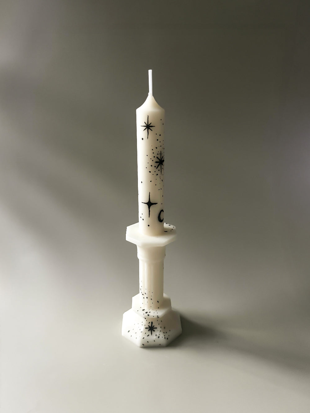 white taper candle with hand painted black moon and stars