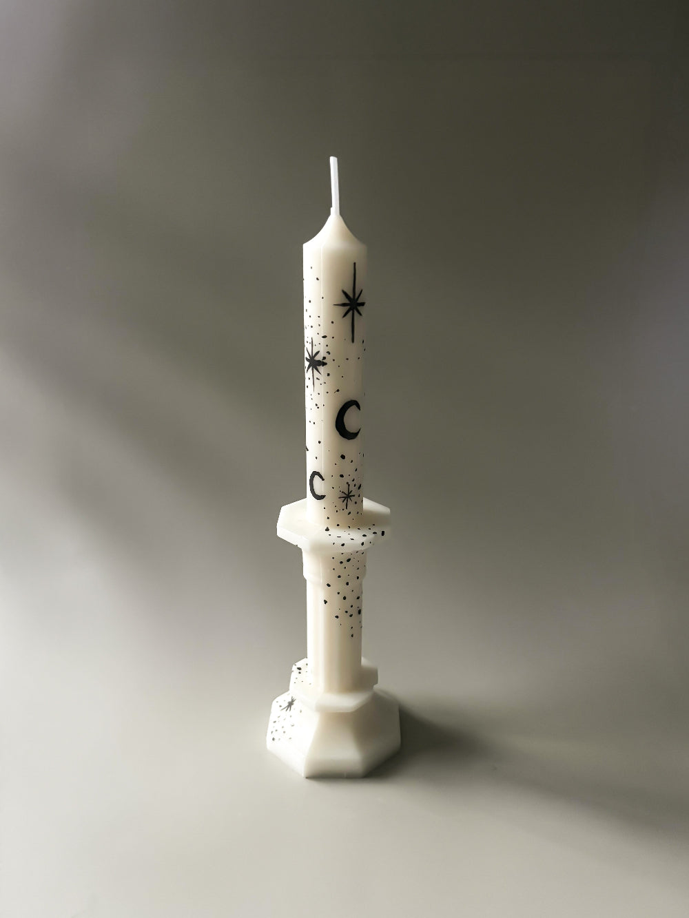 white taper candle with hand painted black moon and stars